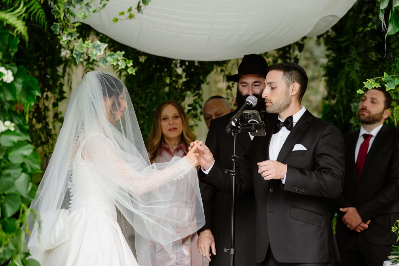 Groom placing wedding ring on bride’s finger